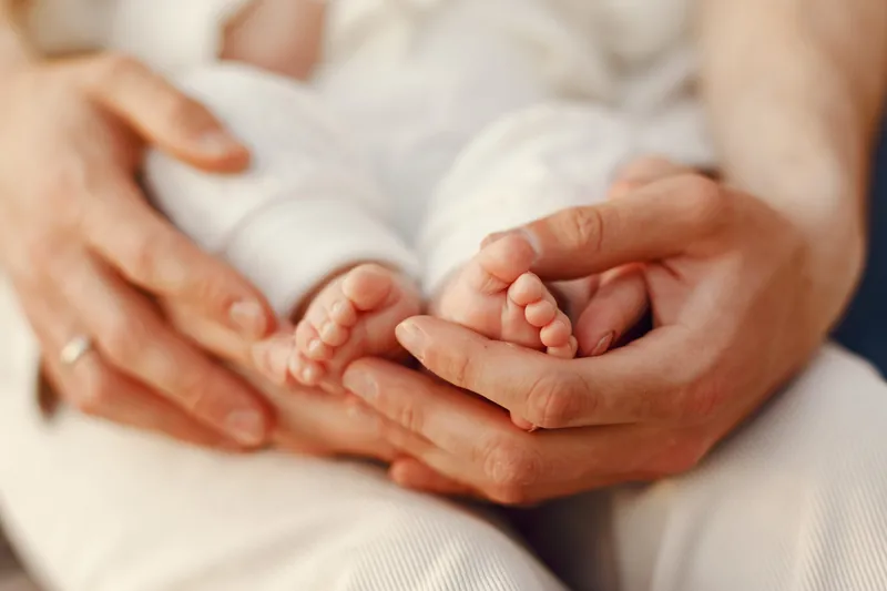 Des mains d'adulte tiennent les deux petits pieds d'un bébé