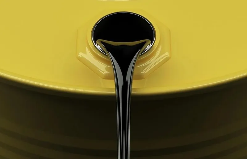 Un filet de pétrole noir et épais s'écoule de l'ouverture d'un baril jaune
