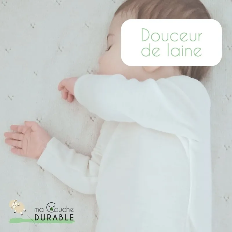 Un bébé en body blanc en laine, allongé sur un plaid tricoté, avec la mention « Douceur de laine » et le logo Ma Couche Durable