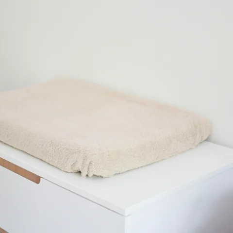 Matelas à langer en housse éponge écrue, seul, vu de biais sur la commode
