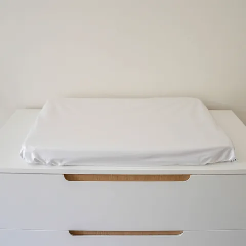 Matelas à langer en housse imperméable blanche, seul sur la commode