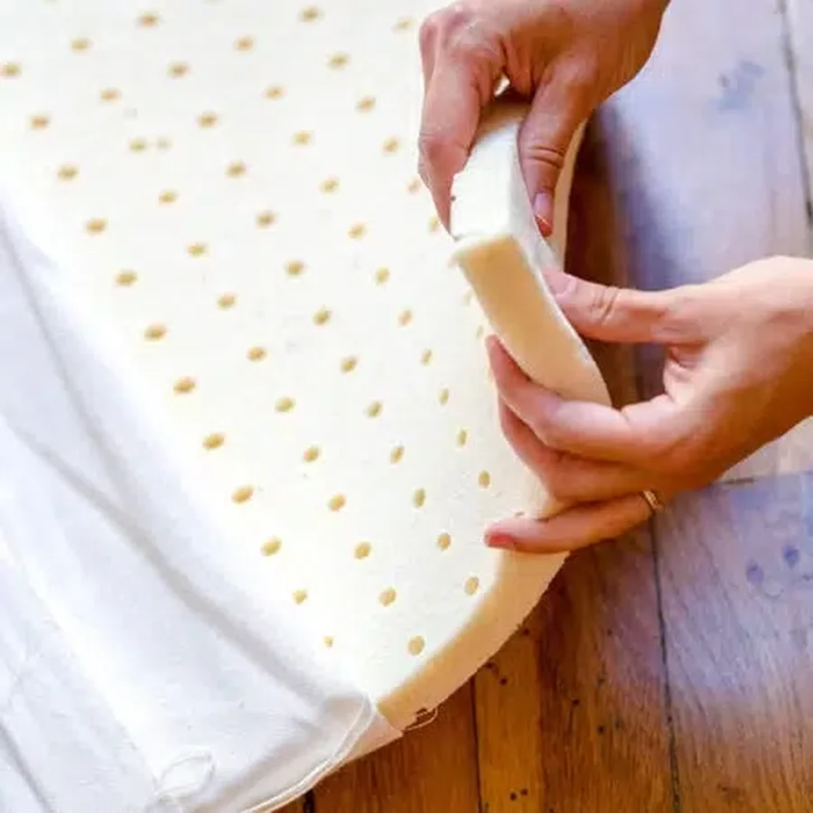 Des mains retirent la housse en coton d'une plaque de latex naturel perforé