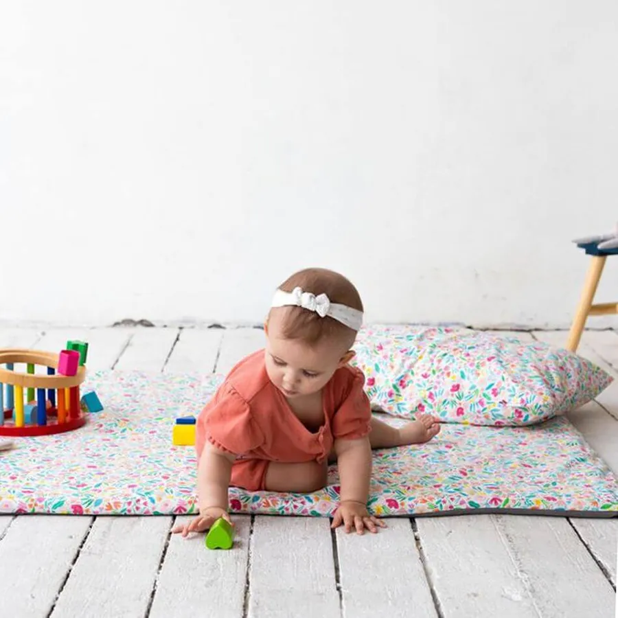 Un bébé allongé sur un tapis d'éveil Jolihuit en latex naturel