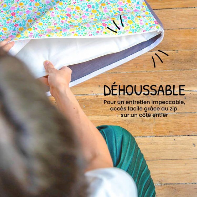 Une main ouvre le zip de la housse fleurie et dégage la mousse. « Déhoussable : pour un entretien impeccable, accès facile grâce au zip sur un côté entier. »