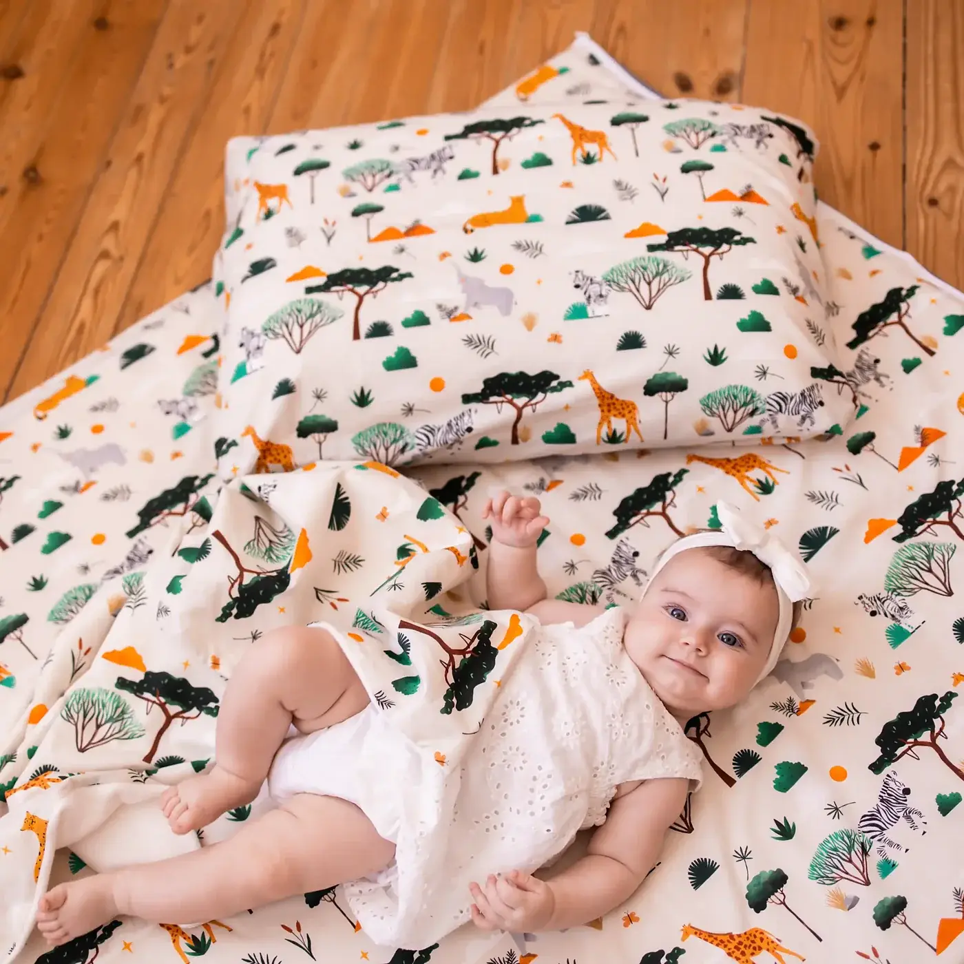 Le Tapis Magique imprimé savane avec son coussin assorti et sa housse repliée, sur un parquet.